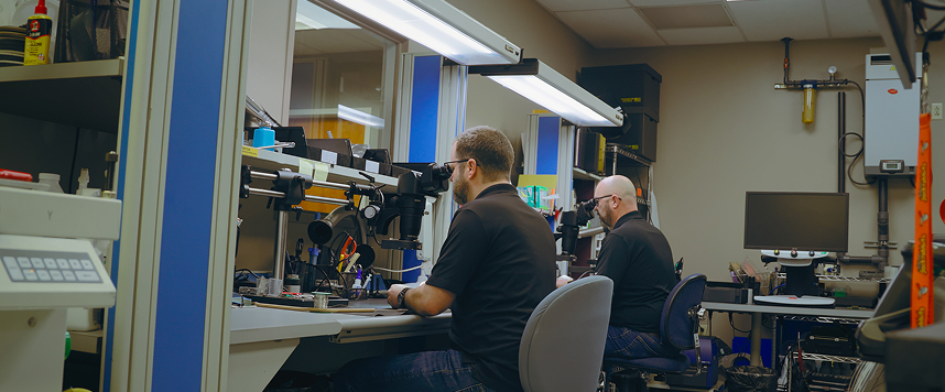 Two Indesign engineers working at microscope stations in the lab