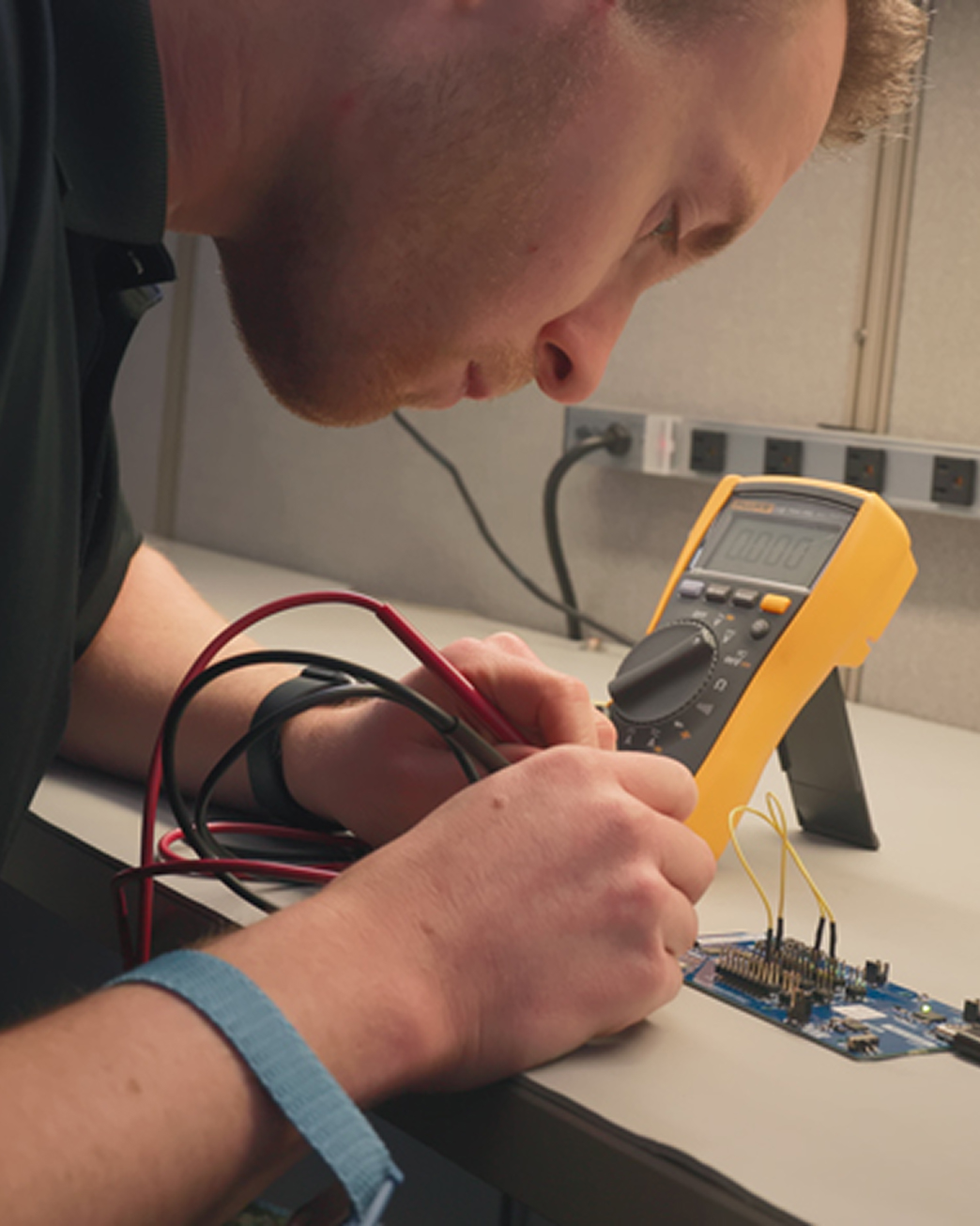 Indesign engineer measuring voltage on a development board with a Fluke multimeter