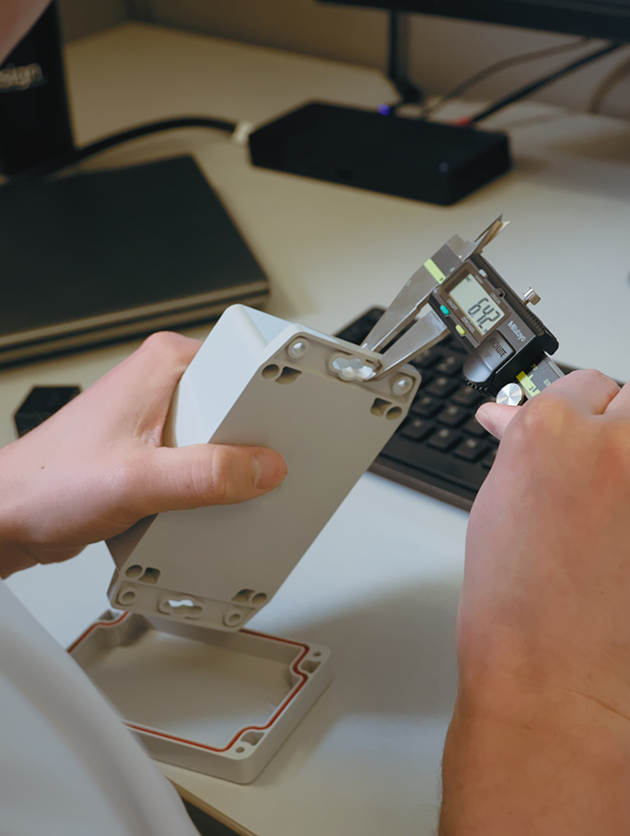Engineer measuring a prototype enclosure with digital calipers